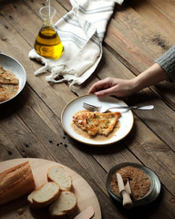 mesa rustica de madera con pollo a la plancha y salsa con la mano de una mujer sujetando el plato
