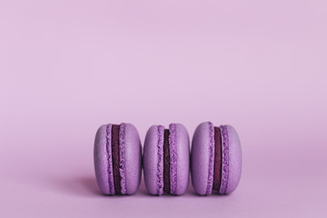 Three french macarons on a purple background. Place for text.