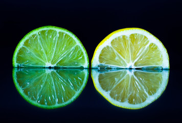 Lime and lemon slice on black reflective background. Creative food concept, minimal style.
