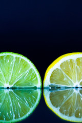 Lime and lemon slice on black reflective background. Creative food concept, minimal style.