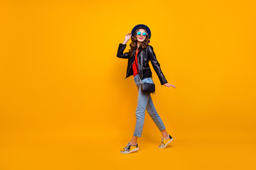Full size photo of charming content girl enjoying promenade have fun wear black leather look outfit denim jeans isolated over yellow color background