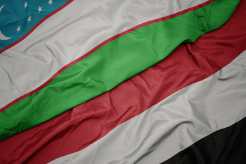 waving colorful flag of yemen and national flag of uzbekistan.