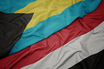 waving colorful flag of yemen and national flag of bahamas.