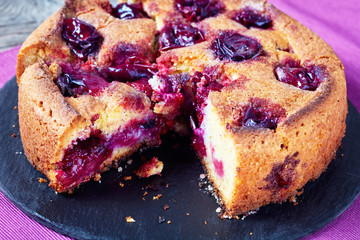 sliced plum torte on a black plate