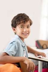 Naklejka premium Schoolboy wearing blue t-shirt sitting at the desk