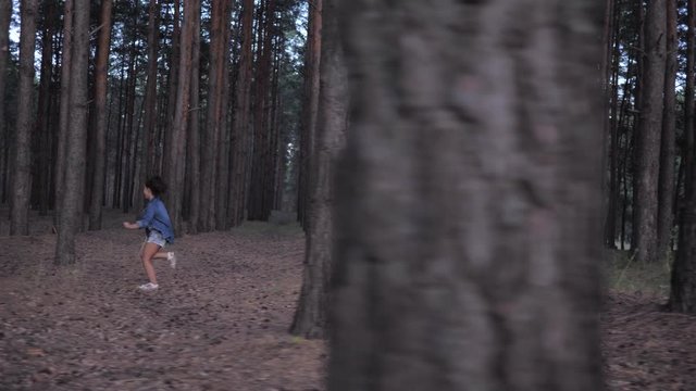 happy relations of family, daddy playing in catch up with kid daughter between rows trees in forest during holidays at evening time in slow motion