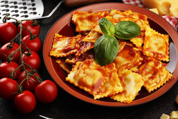 Ravioli with tomato sauce garnished with parmesan cheese and basil on rustic table