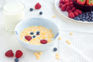 Healthy breakfast of cornflakes with blueberries and raspberries in milk