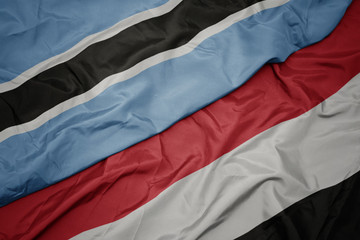 waving colorful flag of yemen and national flag of botswana.