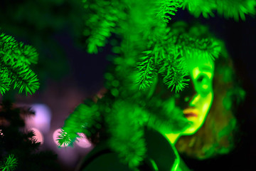 Portrait of a mysterious beautiful woman in green lighting. Festive futuristic concept in trendy color of New year. Selective focus