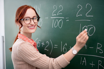 Experienced math teacher standing near blackboard with chalk