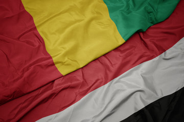 waving colorful flag of yemen and national flag of guinea.