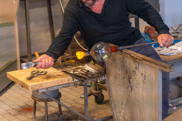 European male artist making glass blowing product at workshop