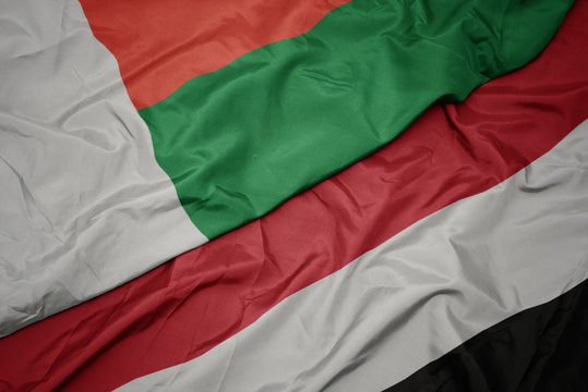 waving colorful flag of yemen and national flag of madagascar.