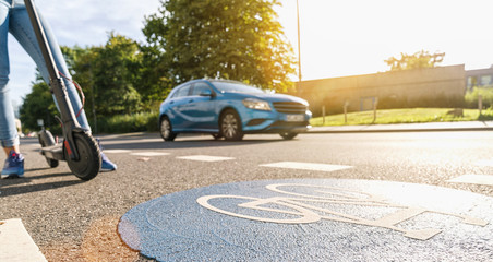 view of a electric kick scooter or e-scooter at a Bicycle road sign with car passing on a summer day, accident concept image