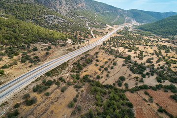 Fototapeta na wymiar Asphalt road in the valley. Countryside highland landscape with agricultural fields and woods, aerial view