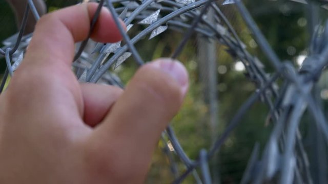 Close Up Of Man Hand Devastatedly Shaking Barbed Wire Fence, Hoping