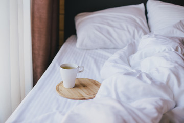 Fototapeta na wymiar Cup of green tea in bed in cozy wooden house.