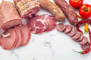 Sausage. A variety of processed cold meat products, on a grey stone.