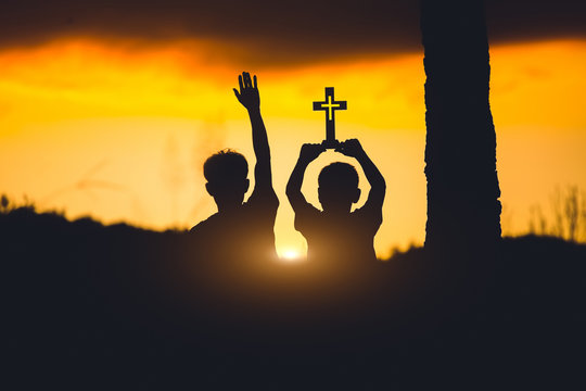 Silhouette of two young christian with cross ,christian concept.