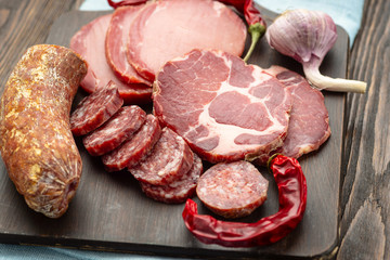 Antipasto platter cold meat with slices ham, beef jerky, salamon wooden board over rustic background
