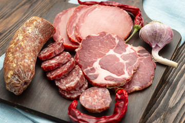 Antipasto platter cold meat with slices ham, beef jerky, salamon wooden board over rustic background