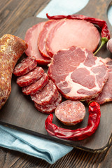 Antipasto platter cold meat with slices ham, beef jerky, salamon wooden board over rustic background