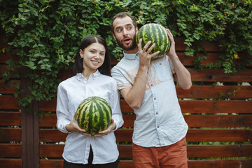 Fototapeta premium Portrait of a happy couple with a watermelon in their hands. Wooden background.