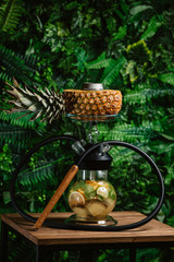  fruit smoky hookah on a pineapple with fruit inside the flask and on a background of greens