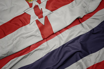 waving colorful flag of thailand and national flag of northern ireland.