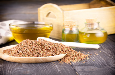 The Sesame oil in glass and seeds on wooden background