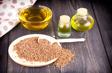 The Sesame oil in glass and seeds on wooden background