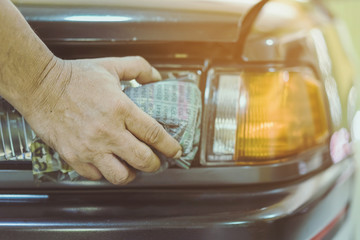 Close up to hand of male worker use wet newspapers to clean the glass part of the car. Selective focus on hand.