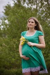 Fototapeta premium portrait of a pregnant young woman in dress in the garden