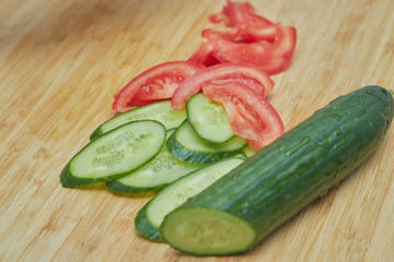 chopped cucumber and tomato on a cutting board. raw healthy vegetables. Vegetable salad.