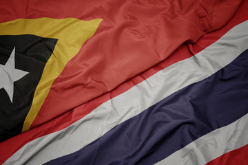 waving colorful flag of thailand and national flag of east timor.