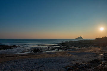 Naklejka na ściany i meble Sunset over Wembury beach with the Mewstone in the distance