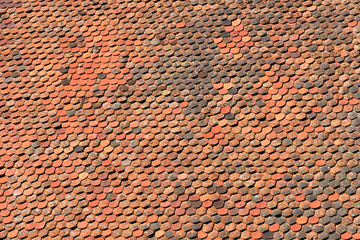 Roof of an old farmhouse in Franconia, Germany, with many red, brown and black tiles in the sun