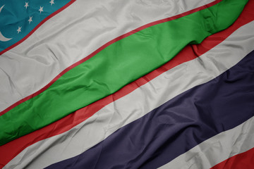 waving colorful flag of thailand and national flag of uzbekistan.
