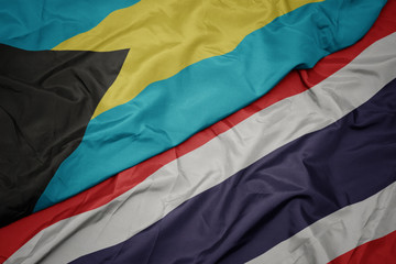 waving colorful flag of thailand and national flag of bahamas.