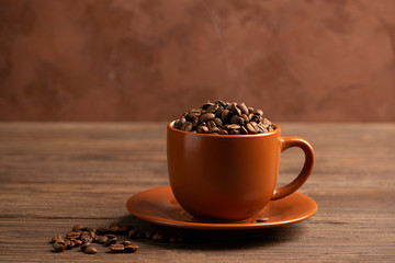Coffee roasted beans in a brown cup a wooden background. Coffee energy drink concept. Selective focus. Horizontal frame