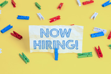 Writing note showing Now Hiring. Business concept for finding evaluating working relationship with future employees Colored clothespin papers empty reminder yellow floor background office