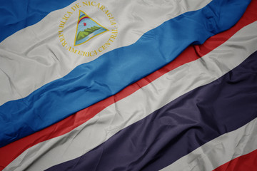 waving colorful flag of thailand and national flag of nicaragua.