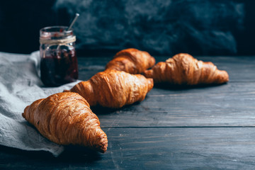 croissants and plum jam on dark wooden table with copyspace