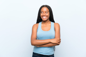 African American teenager girl with long braided hair over isolated blue background laughing