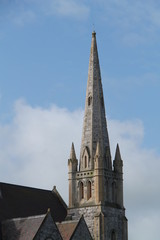 Fototapeta na wymiar The Tall Spire of an Old Stone Built Christian Church.
