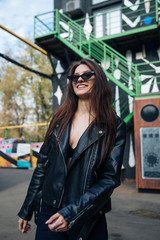 Fototapeta premium young girl in a leather jacket smokes cigarettes, rock style, cheeky and cute girl street posing style, rock punk lifestyle