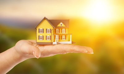 Building, mortgage, real estate and property concept - close up of hands holding house model