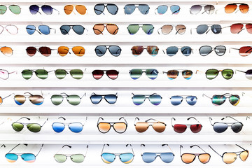 shelves with large number of colorful and fashionable sunglasses on a shop display