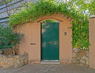 Fototapeta na wymiar elegant house building entrance metallic green door and ocher wall fence, Athens Greece